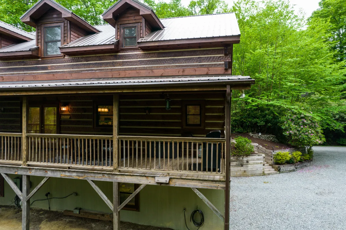 A cozy wooden balcony attached to a log cabin overlooks dense greenery, inviting guests to relax outside and take in the surrounding nature. The architecture ties the cabin to its mountain setting.