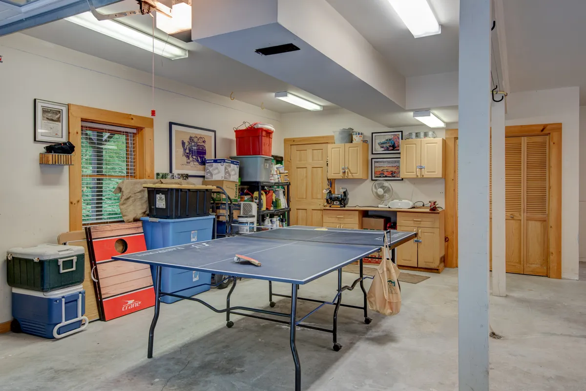 The image features a spacious area with a ping pong table, storage units, and a kitchenette. The casual setting is ideal for friendly matches and family gatherings, reinforcing the game and recreation focus of the section.