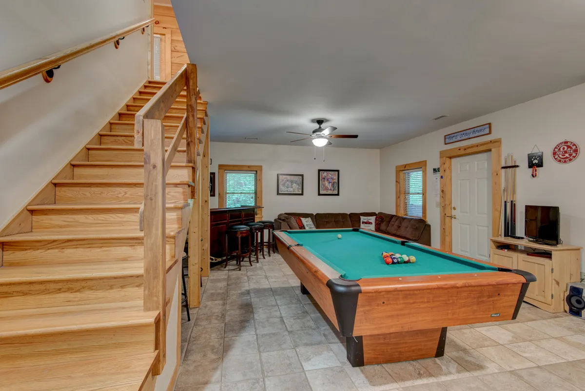 An inviting interior game room with a pool table, bar seating, and a comfortable couch. The setting is perfect for friendly competitions, movie nights, or group games, providing a lively space for family bonding and entertainment.